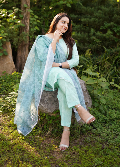 Woman in a light green outfit sitting on a stone bench in a garden.